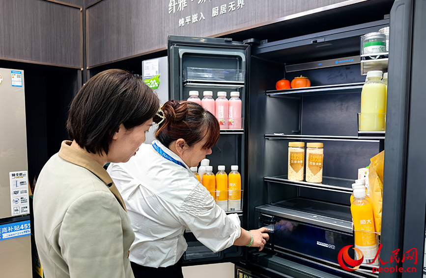 商场导购员向消费者介绍智能冰箱。人民网 冯肖慧摄