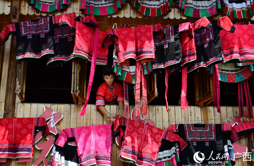 瑶族妇女在吊脚楼上晾晒花衣花裙。 