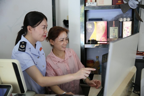 图为“富小税”团队成员为顺发水库鱼饭店详细解读增值税减免等政策，“手把手”辅导开具增值税发票。王丽芸摄