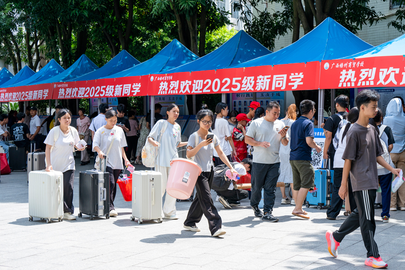 新生在家長的陪伴下搬運行李物品，走進校園。何華文攝