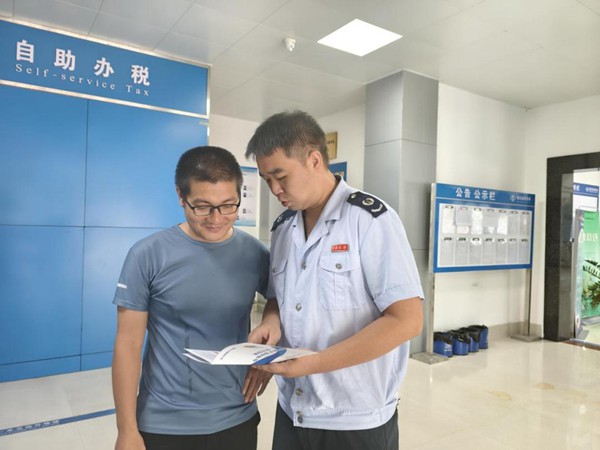 图为税务工作人员正在为农户讲解与农产品相关的税费优惠政策。覃月枫摄