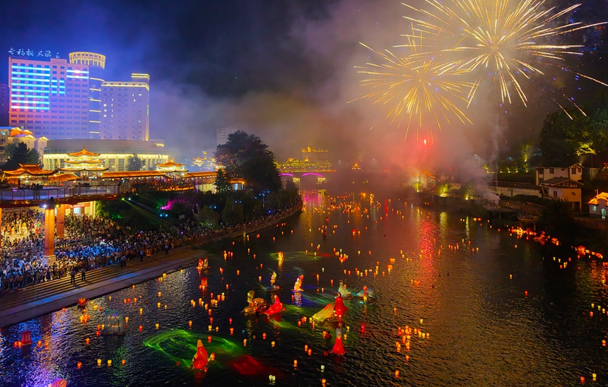 夜幕下,河面河灯流光溢彩,天空烟花璀璨夺目,尽显节日的欢快与热闹。