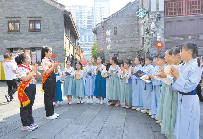 在中华大戏院门前,南宁市华强路小学的学生们齐声念童谣。记者宋延康摄
