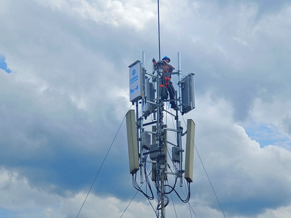 作业人员登上通信桅杆塔，进行5G-A通感一体基站安装作业