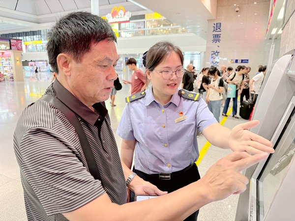 圖5：南寧東站售票值班員引導旅客在自助售票機上辦理改簽手續。於莉攝