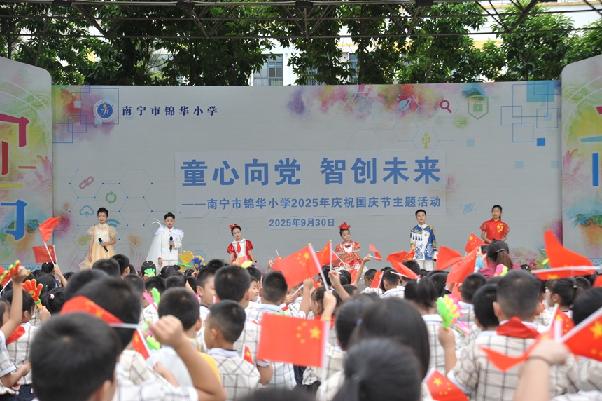 全体师生挥舞手中国旗，齐声高唱《我和我的祖国》。南宁市锦华小学供图