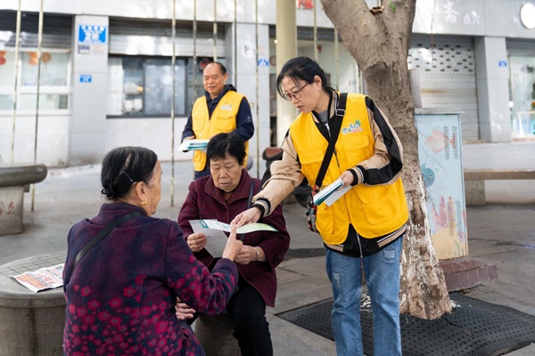 志愿者向社区居民发放用电安全手册