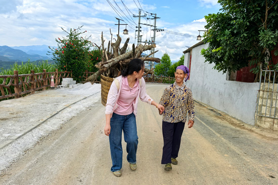圖為金存英幫助年長村民背送柴火。楊進宏 供