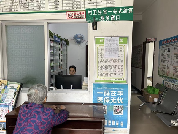 村(社区)卫生室医务人员为购药群众进行医保“一站式”结算服务