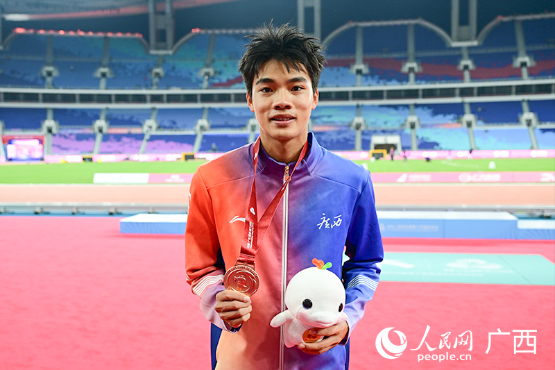 曾克理手持獎牌和吉祥物。人民網 雷琦竣攝