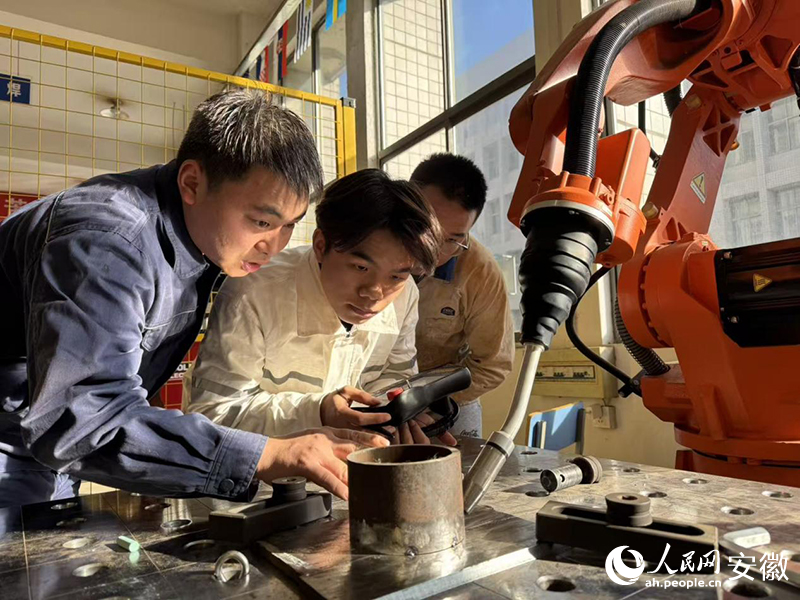 盛云亮（左）指导同学进行机器人焊接
