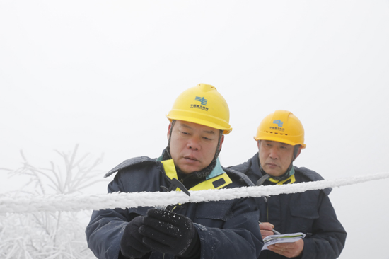 南方电网广西桂林供电局工作人员在现场查看覆冰情况，为开展110千伏中两线直流融冰提供精准现场数据。谢忠敏摄