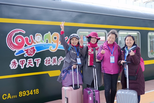 旅客在“桂行天下”旅游专列前合影。丁明宇摄