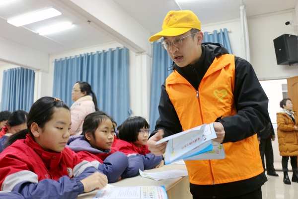 青年志愿者为小学生发放护路宣传单。覃晓平摄