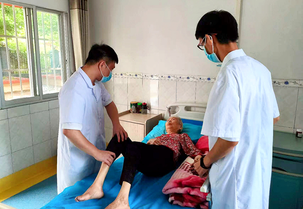 广西武宣县东乡镇河马卫生院医养结合服务院医务人员为医养老人开展推拿疗法。