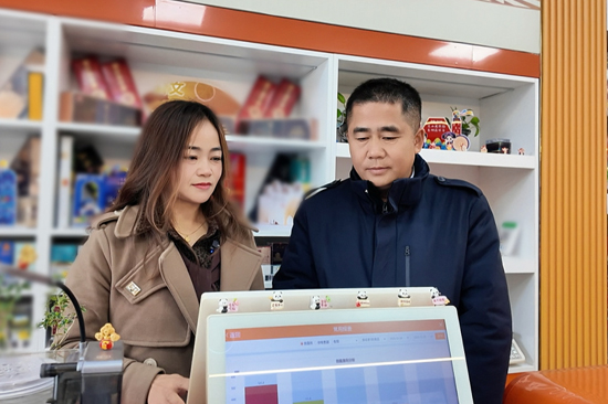 宁明烟草客户经理指导黄丽利使用终端数据系统。雷蕾摄）