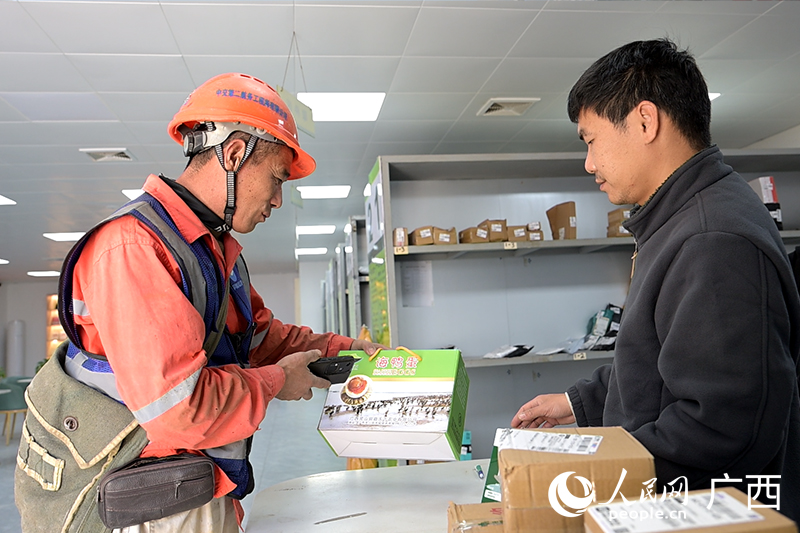 李華峰(左)給家裡寄廣西海鴨蛋。人民網記者 雷琦竣攝