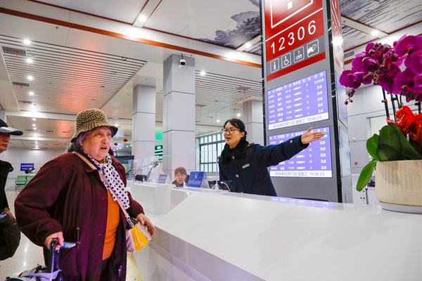 圖為:桂林北站“劉三姐·漓江情”服務台工作人員熱情引導老年旅客候車。(蘇展 攝)