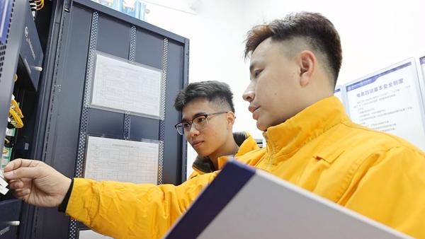 莫景元(右)在給徒弟陸任良(左)教學光纜業務知識。黃繽瑤攝