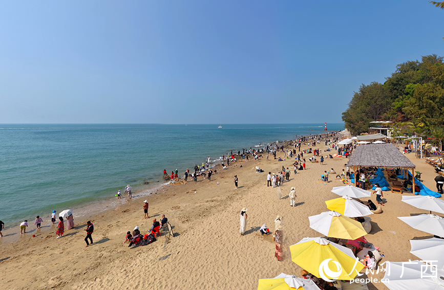 游客在北海冠嶺夕海岸海灘游玩打卡。人民網記者 付華周攝