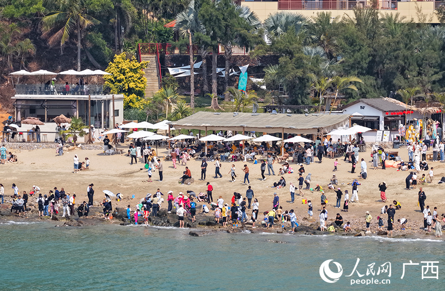 游客在北海冠嶺夕海岸海灘游玩打卡。人民網記者 付華周攝