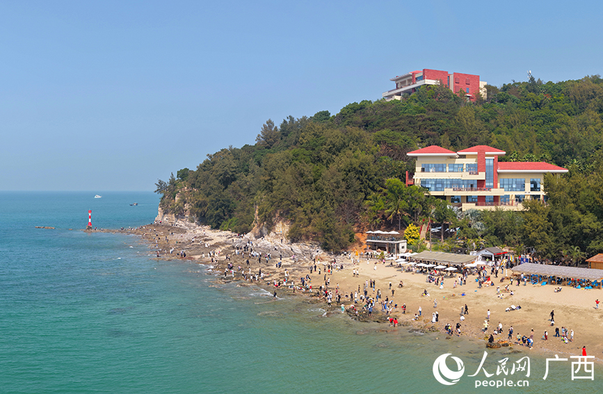 游客在北海冠嶺夕海岸海灘游玩打卡。人民網記者 付華周攝