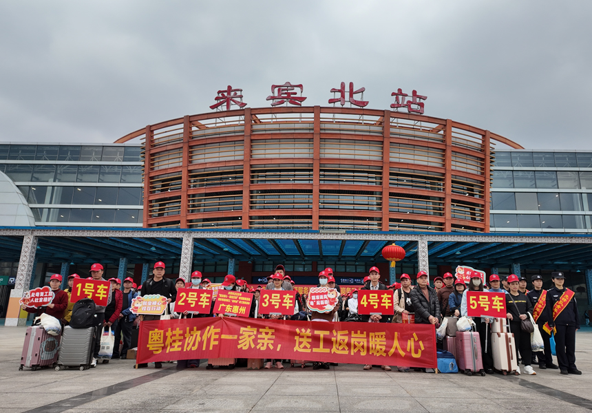 務工返崗人員在車站門前合影。李伊攝