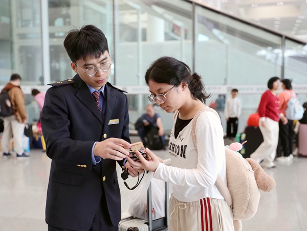 南宁东站客运员为学生旅客解答问讯。麦竹娴摄