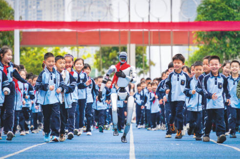 3月2日,南寧市天桃實驗學校教育集團青運校區舉行2026年春季學期開學典禮。在“開學第一跑”活動上,學生們和宇樹機器人一起在操場上快樂奔跑。 本報記者葉子榕 攝