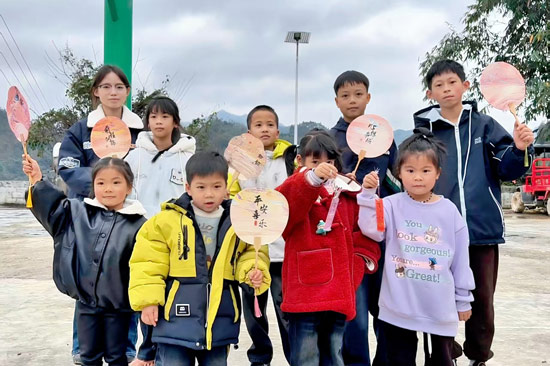 平吉村儿童展示自己手工做的漆扇。田林县委宣传部供图