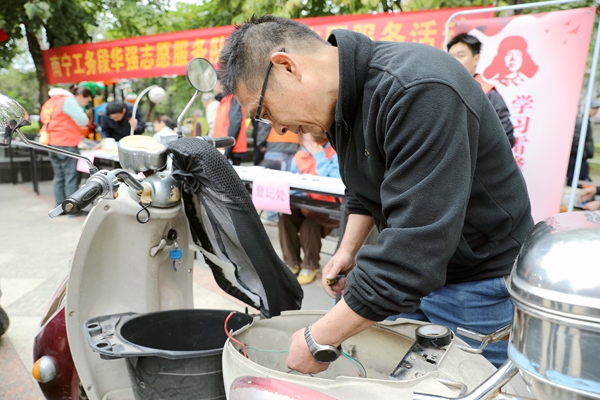 华强志愿服务队队员为居民修理电动车。庞敬业摄