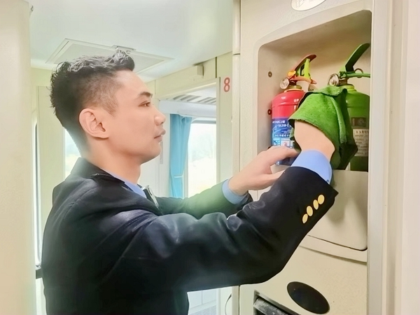 列车员黄昌鹏擦拭认真擦拭、检查车厢灭火器，确认设备状态良好。董晖  摄