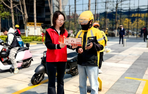 工作人员向快递小哥介绍金融知识。平安产险广西分公司供图