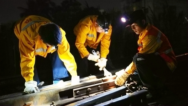 作業人員正在安裝鋼軌扣件。陳健攝