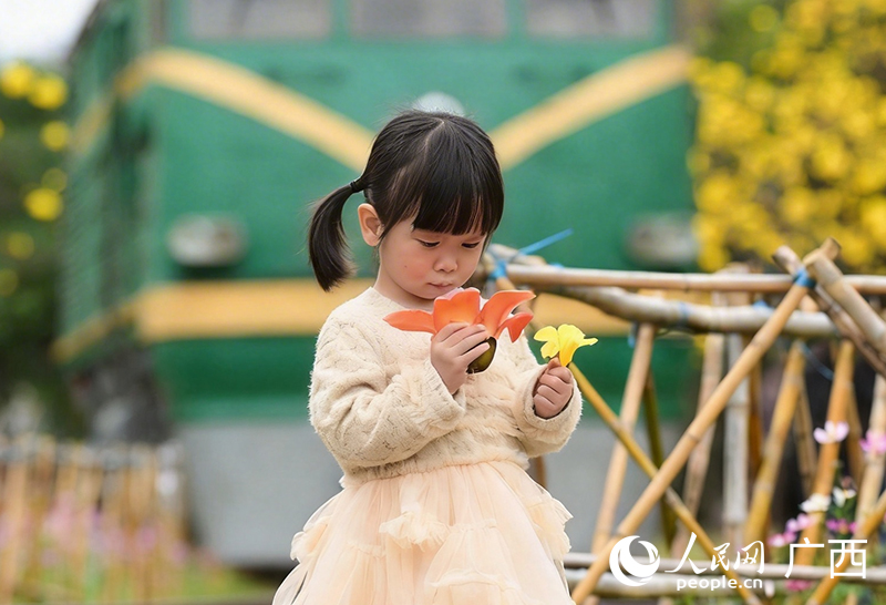 小朋友在南宁市江南公园拾起落在地上的花朵。人民网记者 雷琦竣摄