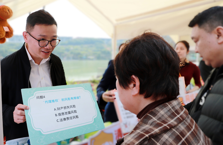 平安产险广西分公司党委书记杨晋峰（左）与群众进行答题互动，讲解金融知识。平安产险广西分公司供图
