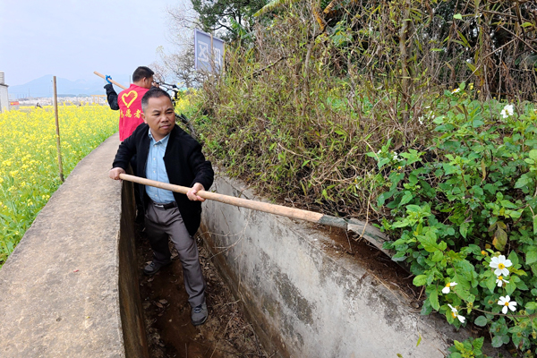 党员干部群众在清理水渠边的杂草。