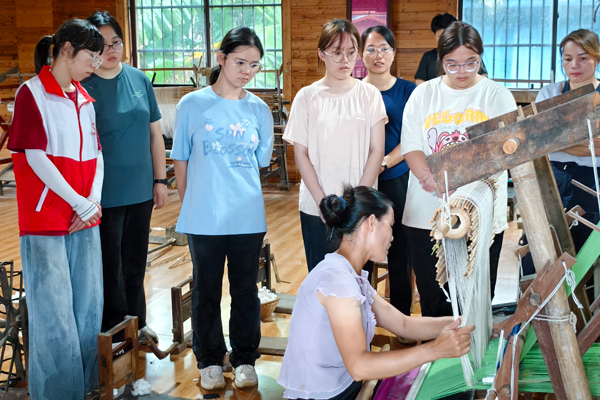 壯錦工坊負責人李東梅正向研學團隊展示織錦技藝。