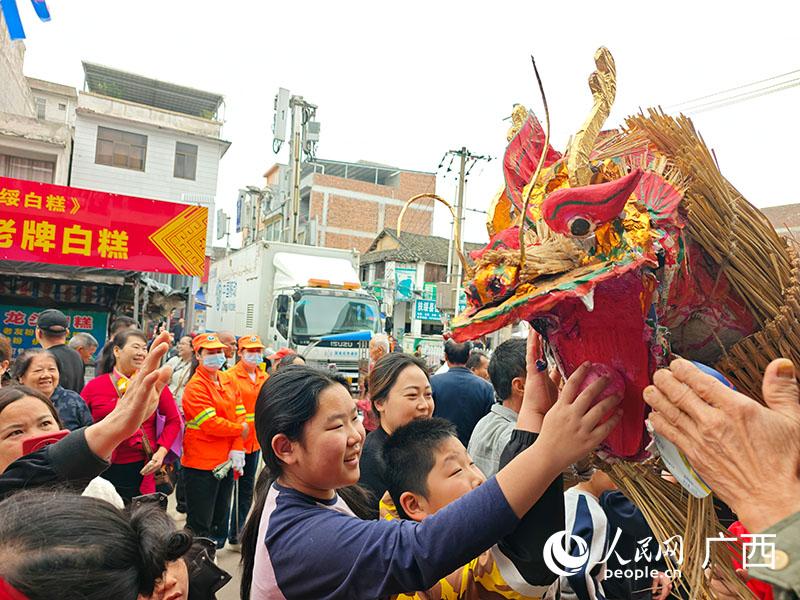 当地群众与孩童争相触摸龙头，在欢声笑语中祈福。人民网记者 沈泉池摄