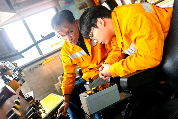 新入路青工温家彤在现场师傅指导下学习业务操作。