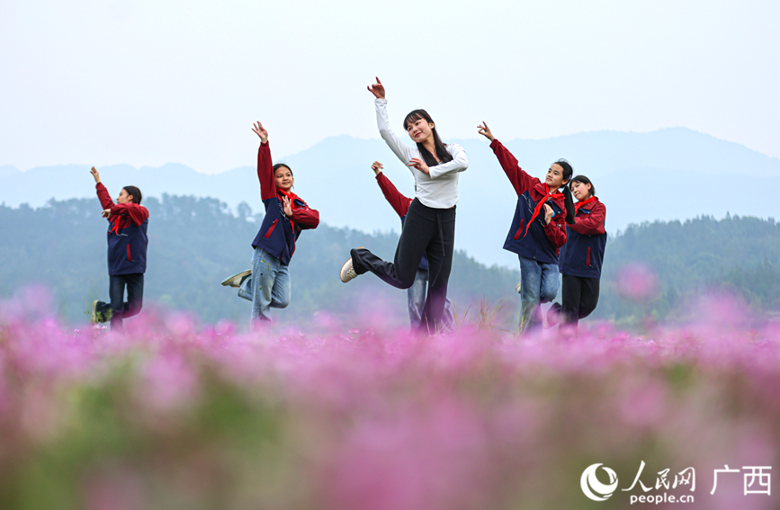 孩子们和老师在紫云英花海跳舞。