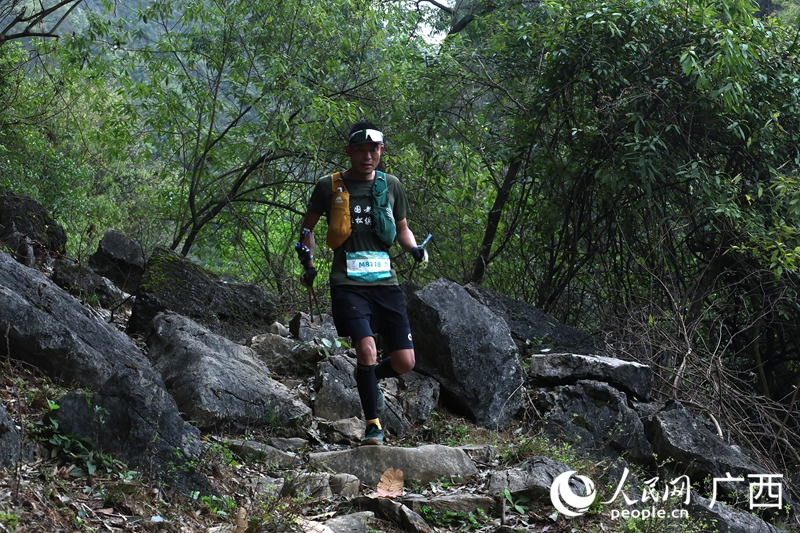 選手手持登山杖，在崎嶇的山石賽道上攀登。人民網 龐惠文攝