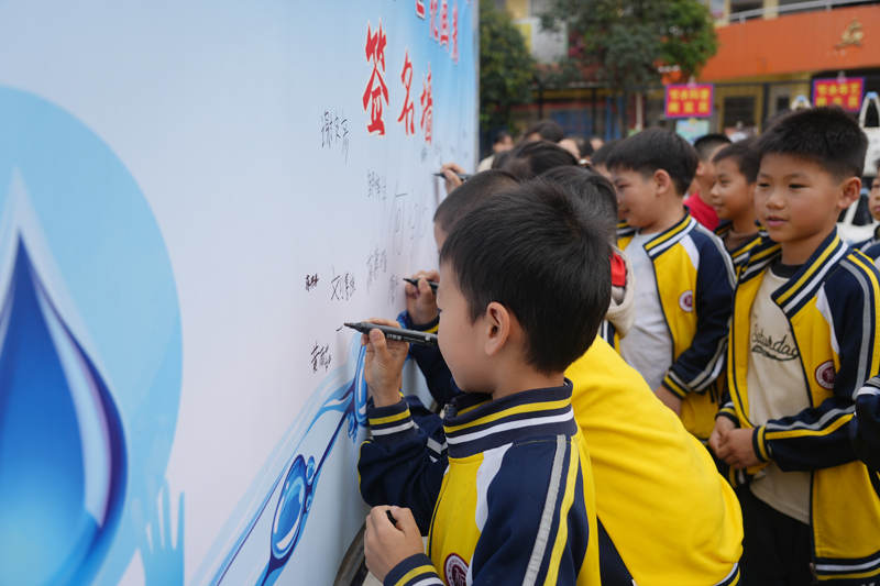 同學們在節水承諾簽名牆上鄭重簽名。