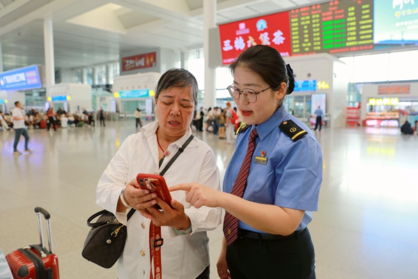 南宁东站工作人员解答旅客问询。