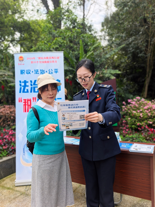 宣传展台前,税务干部向群众讲解便民办税缴费举措。黄骞摄