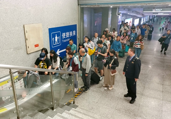 图为:桂林北站工作人员在出站电梯口引导游客有序乘梯。郑长贤摄