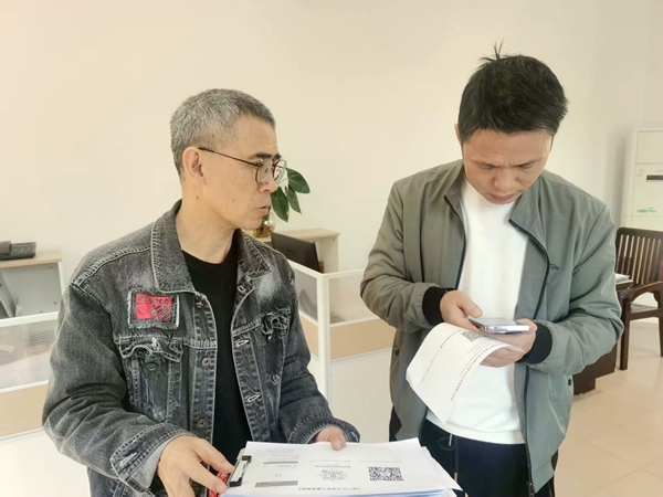 图3：该公司的职工为客户讲解新程序的使用说明书。陈美珍摄