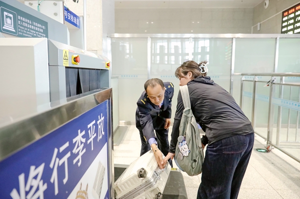 桂林车站客运职工协助旅客行李过机安检。郑长贤摄