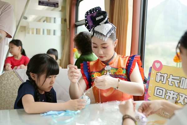 Z6次列车工作人员与小旅客一起制作非遗绣球。曹烁摄