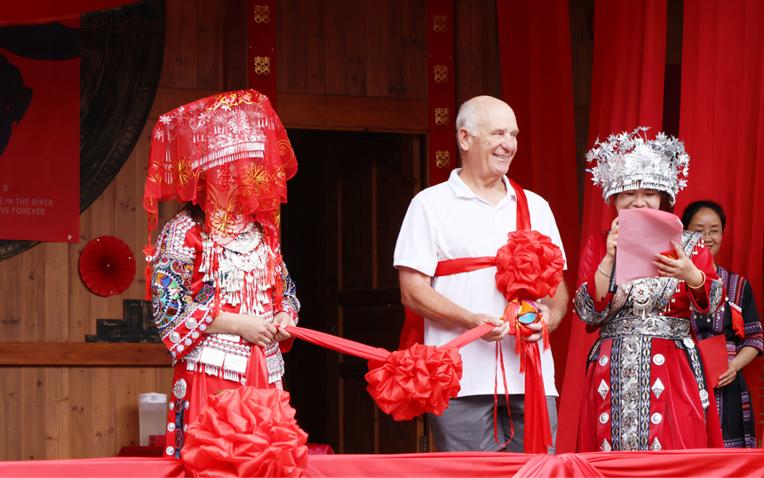 外国游客幸运接住绣球，被现场的红绸与欢呼声簇拥上台，体验一场别开生面的苗家婚俗仪式。